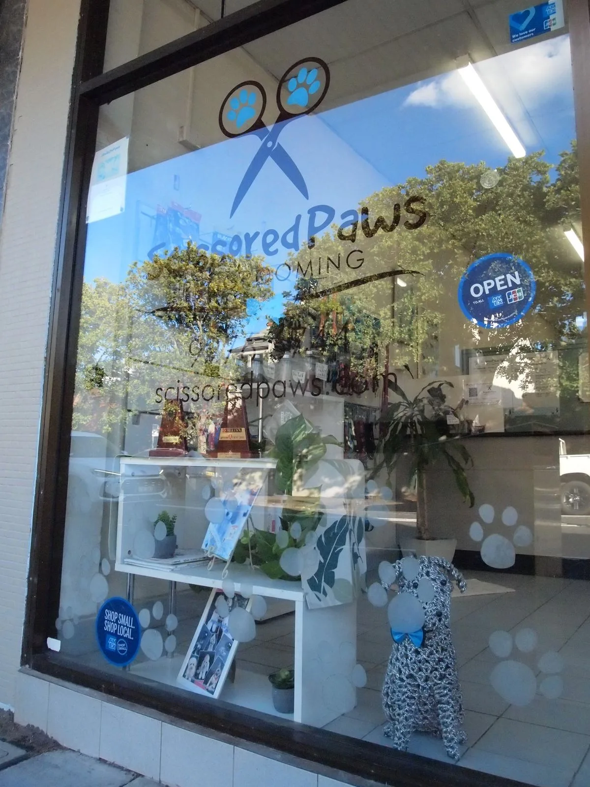 Scissored Paws shopfront window on Pittwater Rd, Manly, with the logo decal and open sign